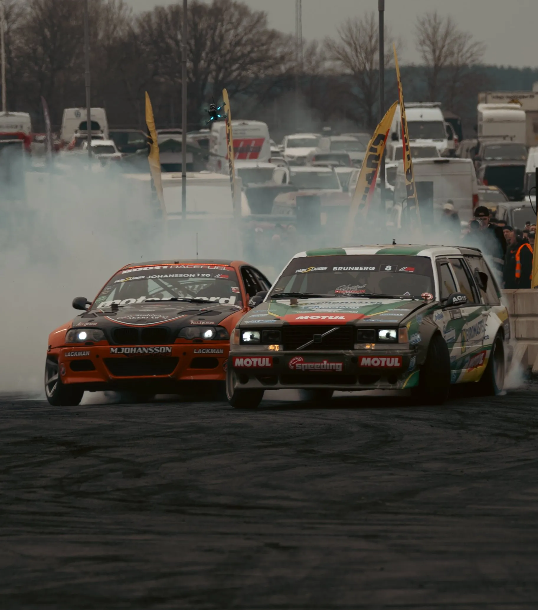 Orange BMW and a Volvo estate drifting in tandem