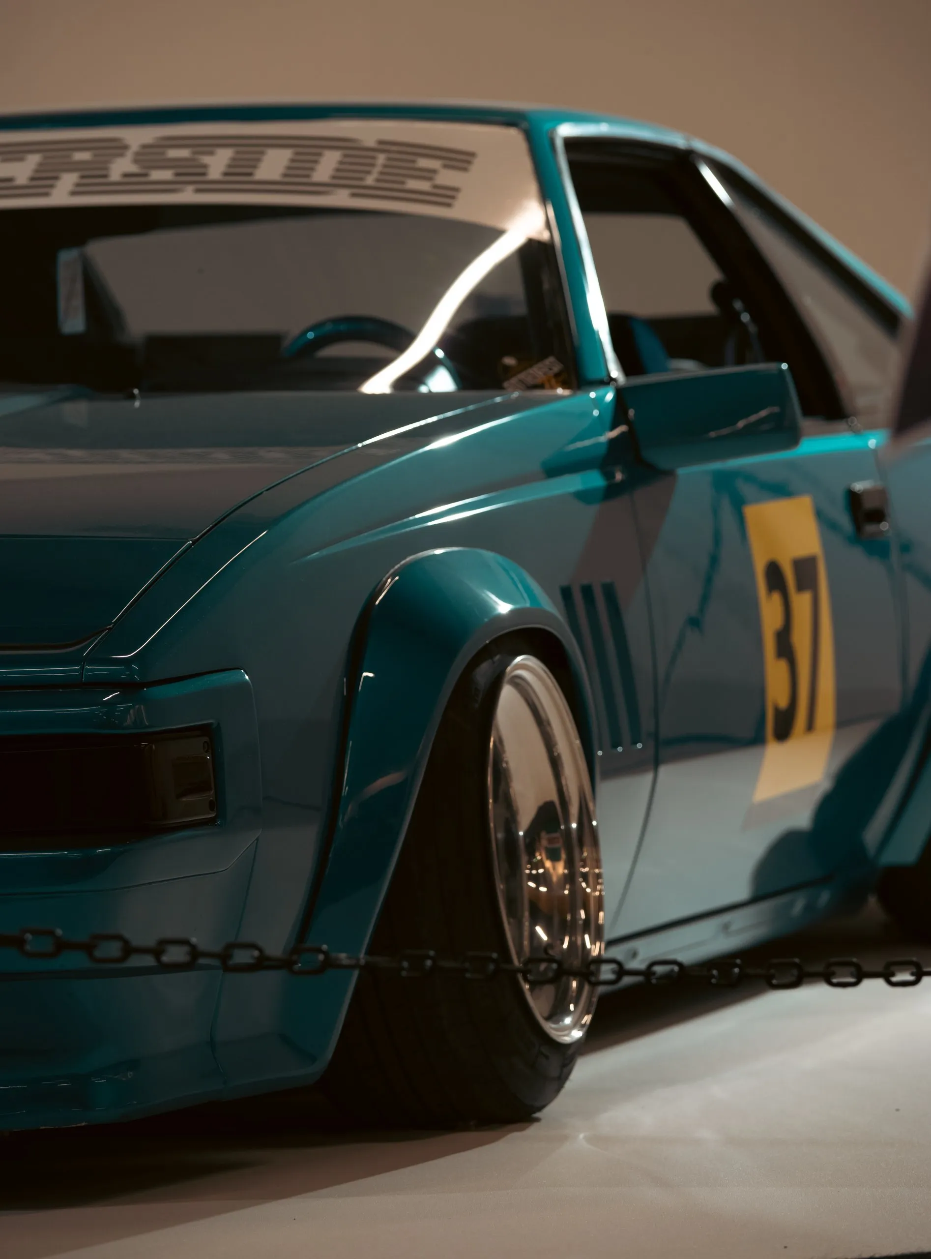 Turquoise car with race number 37 and wide fenders