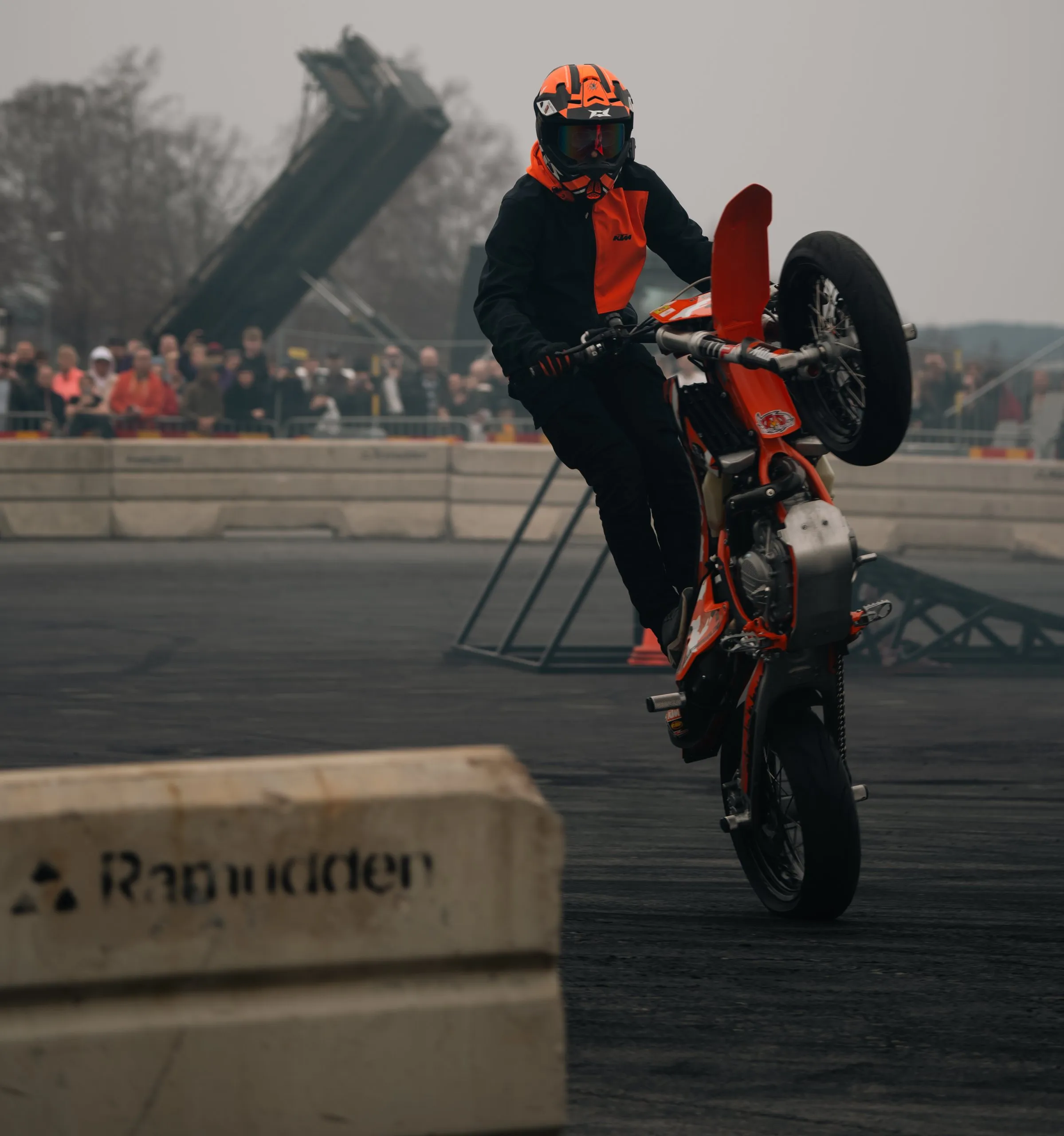 Stunt rider on the rear wheel of an orange KTM
