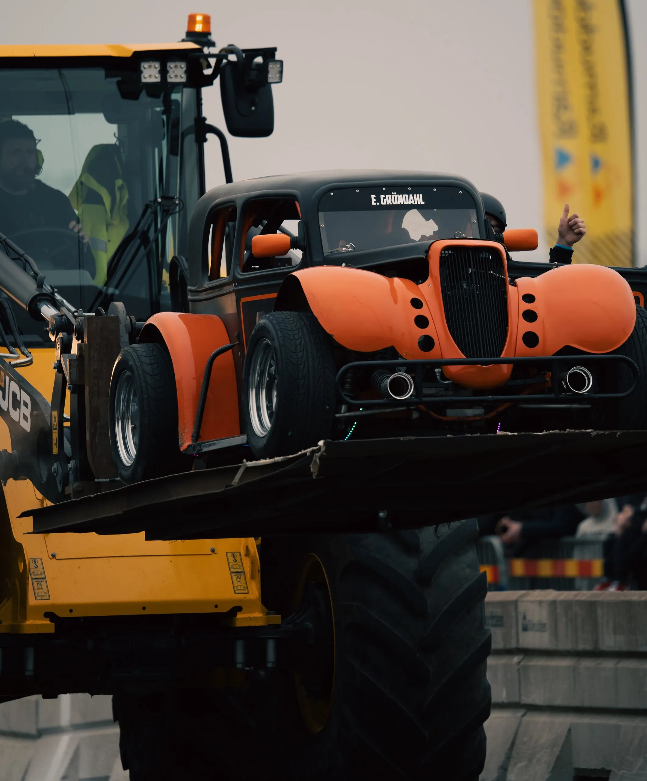 Orange and black hot rod lifted by a wheel loader