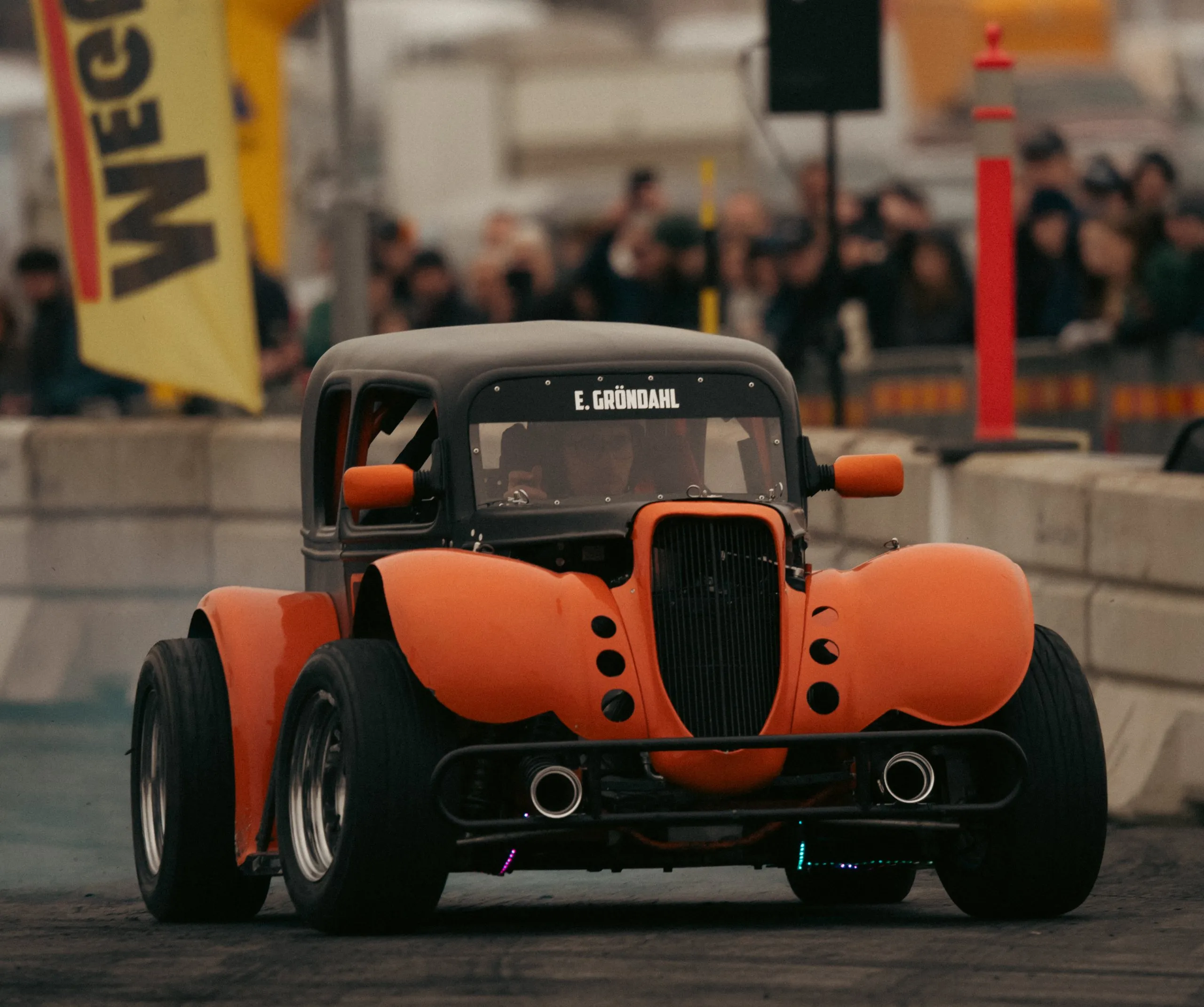 Hot rod with orange fenders, head on