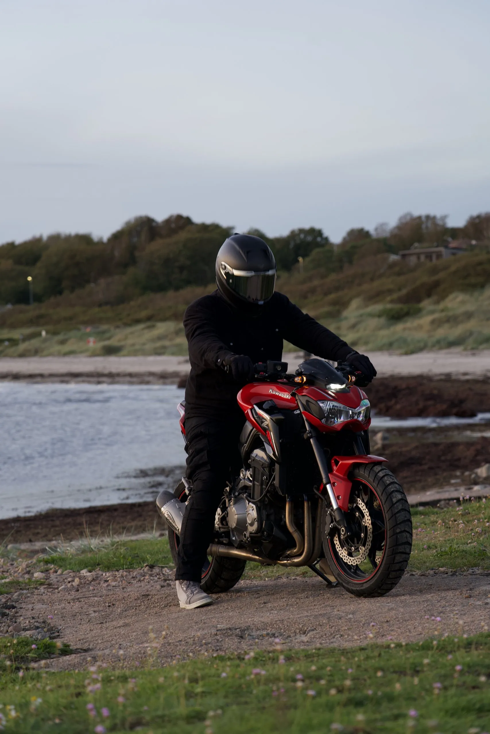 Rider on a red Kawasaki Z900 by the beach