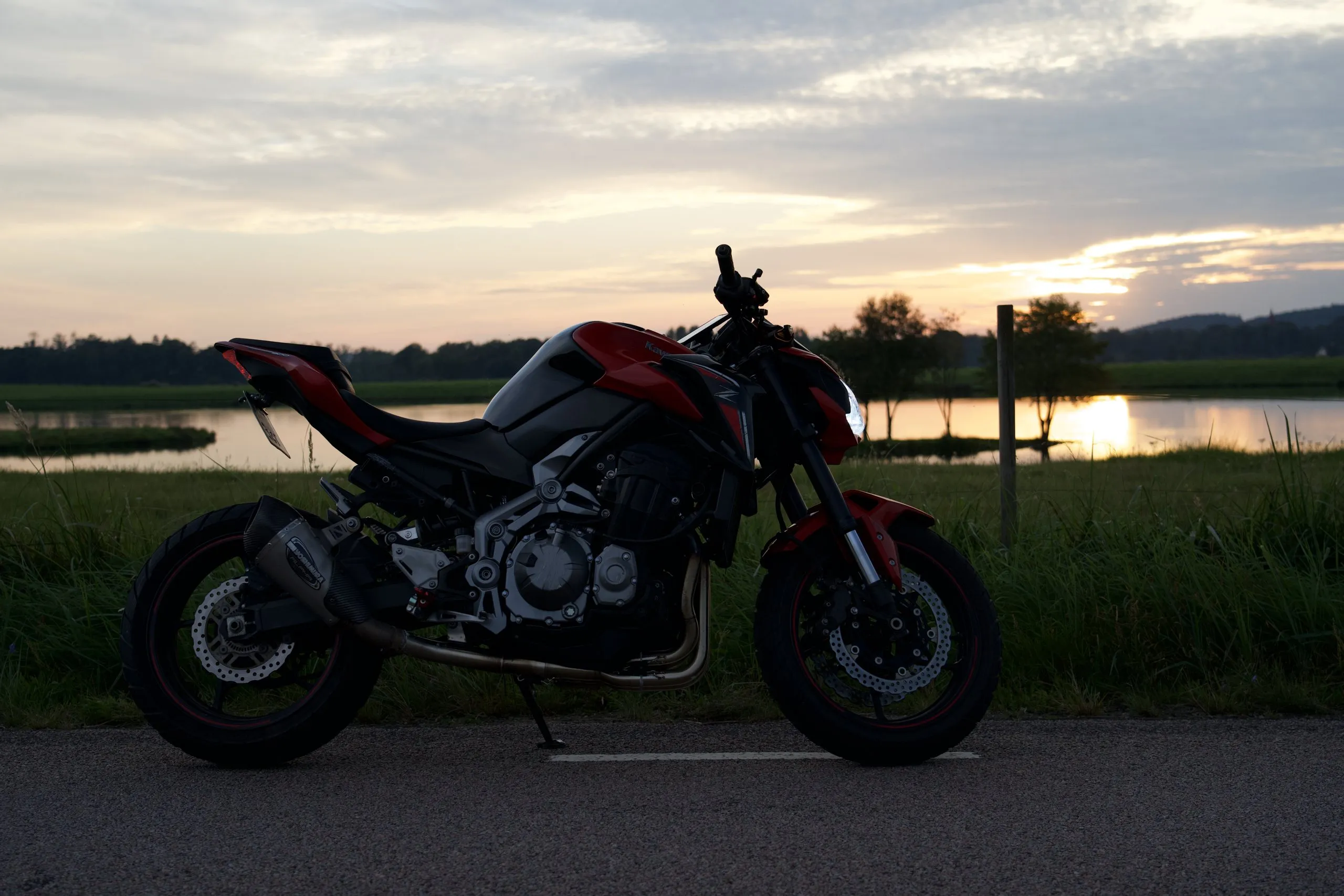 Red Kawasaki Z900 by a lake at sunset